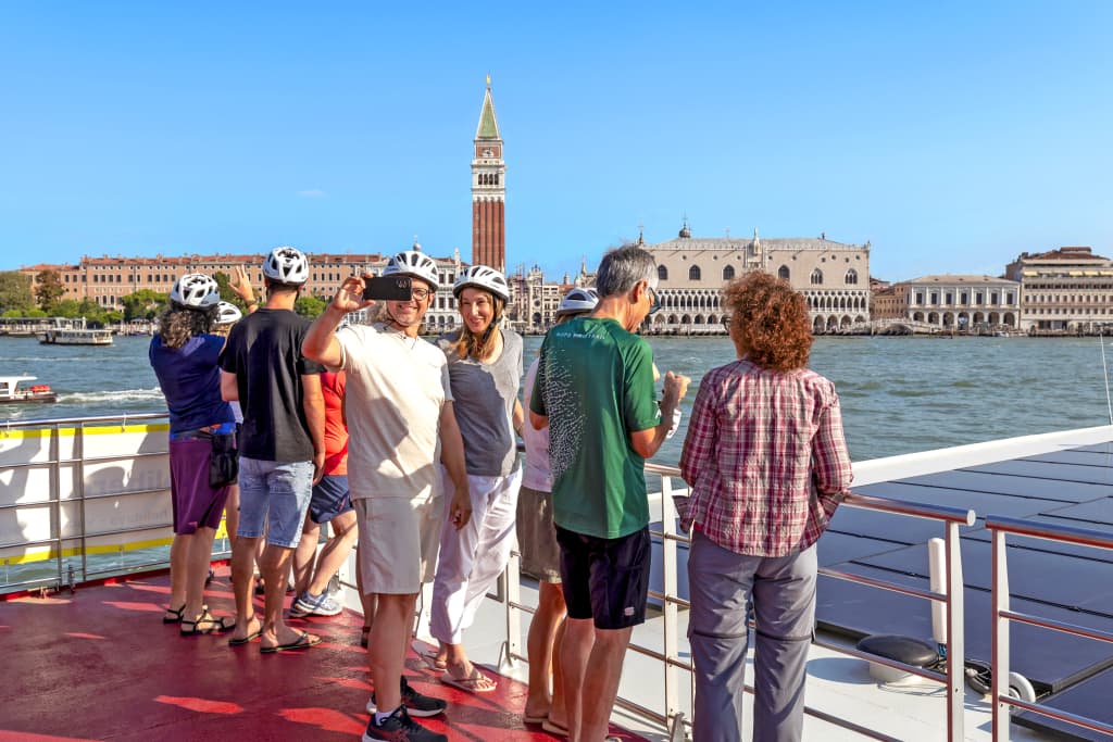 Gruppo di persone sul ponte di una nave con vista su San Giorgio Maggiore e la laguna di Venezia