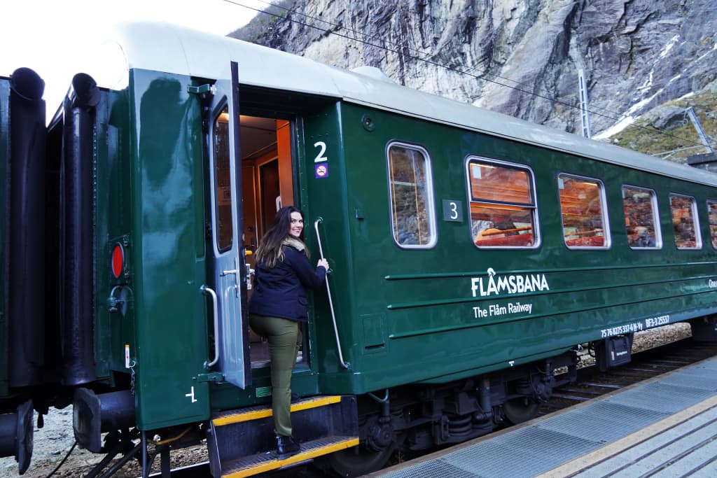 Treno verde della linea Flåmsbana fermo alla stazione di Myrdal, con sfondo montuoso norvegese.