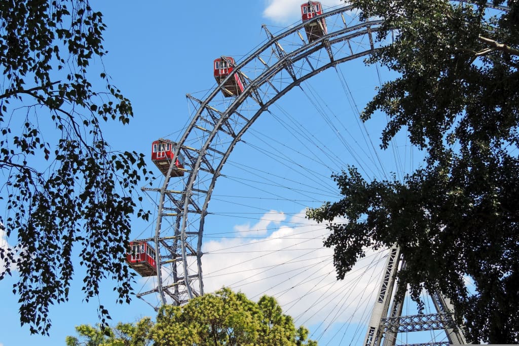 La ruota panoramica Wiener Riesenrad al Prater di Vienna vista tra gli alberi in una limpida giornata estiva