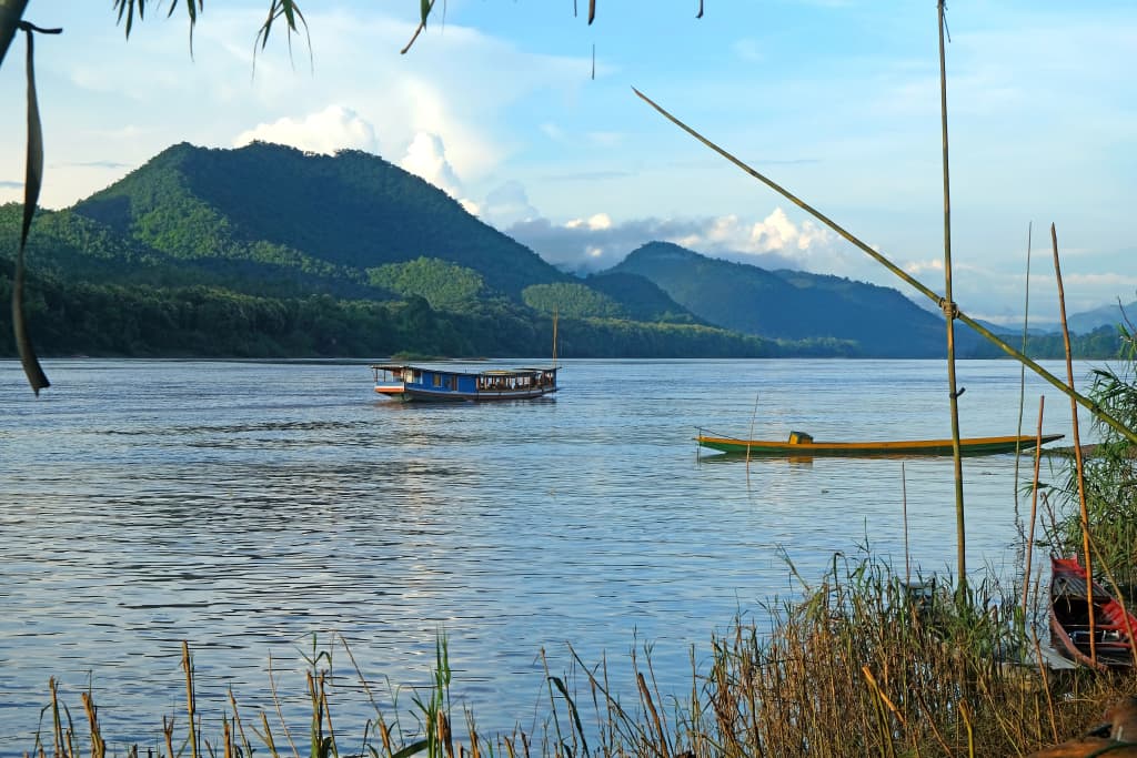 Imbarcazioni sul fiume Mekong al tramonto con le montagne di Nong Khiaw, Laos settentrionale – paesaggio fluviale panoramico