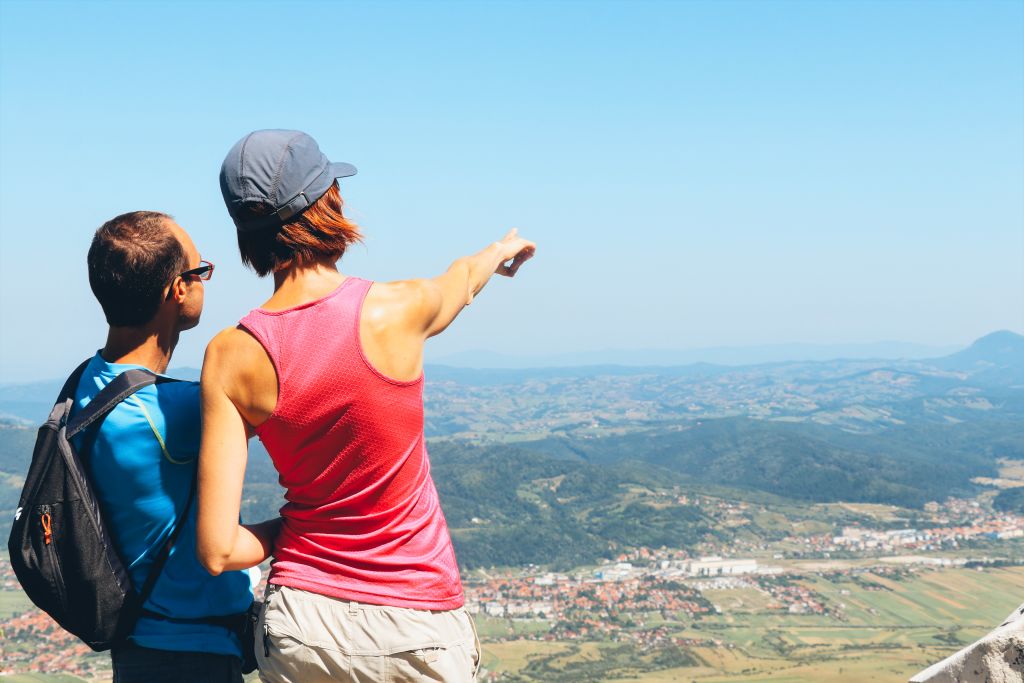 Coppia di escursionisti intenti a osservare il panorama da una cima di montagna, trekking in Romania tra le terre del conte Dracula