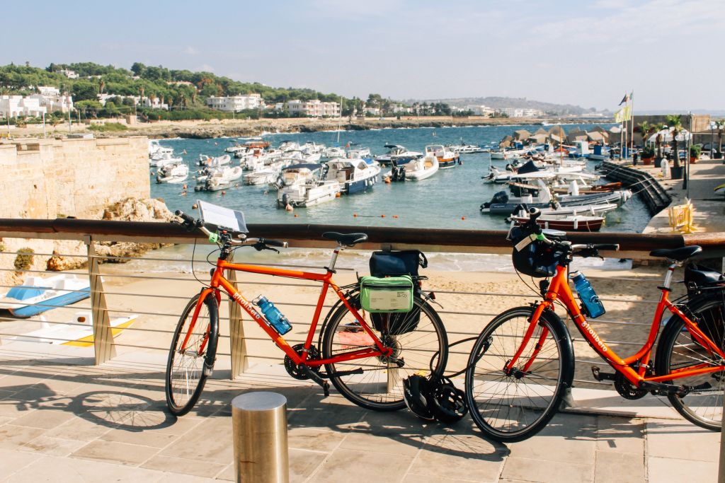 Bicycles parked in front of a harbor with boats, Italy.