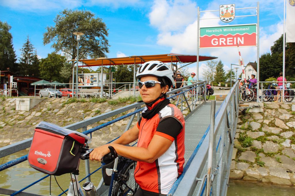 Cicloturista con bici "Girolibero" con caschetto e bici a mano, scendendo dal traghetto a Grein, fiume Danubio, Austria