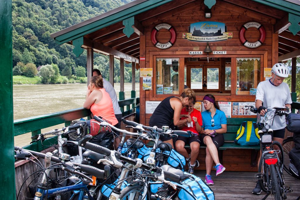 Cicloturisti intenti ad attraversare il Danubio con il traghetto, bici con borse, relax, Austria