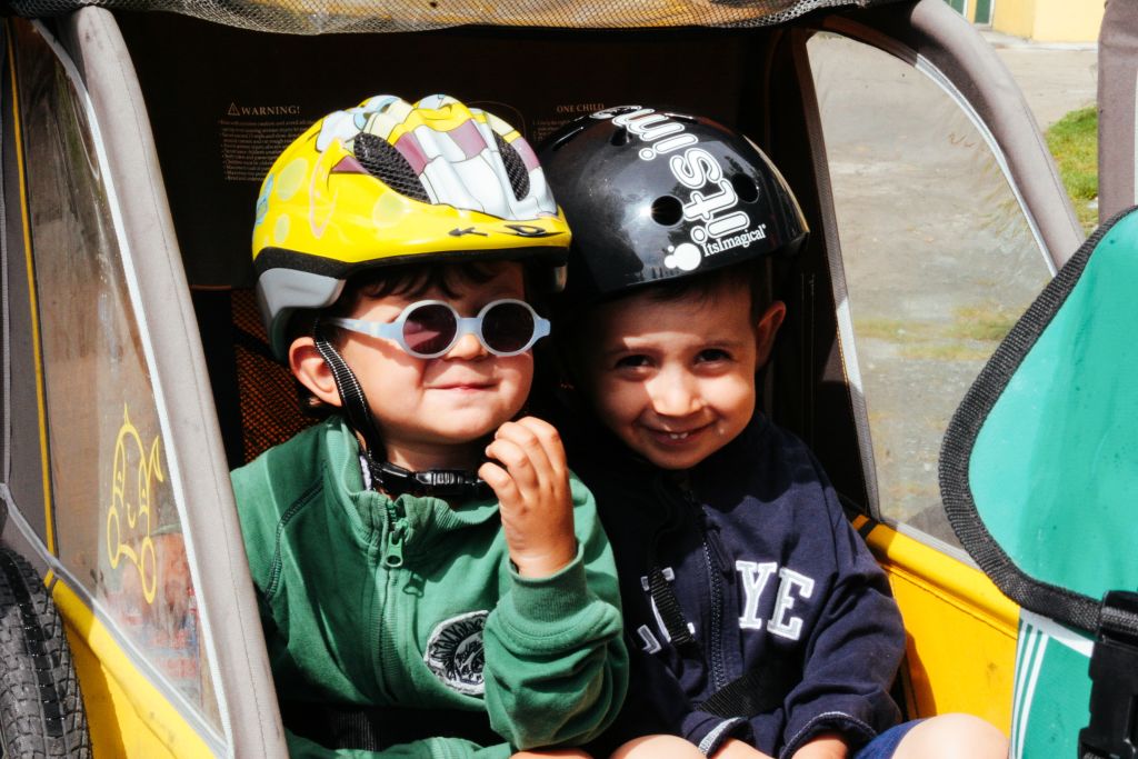 Bambini con caschetto nel carrellino di una bici, divertimento, vacanza per famiglie, tra Austria e Germania