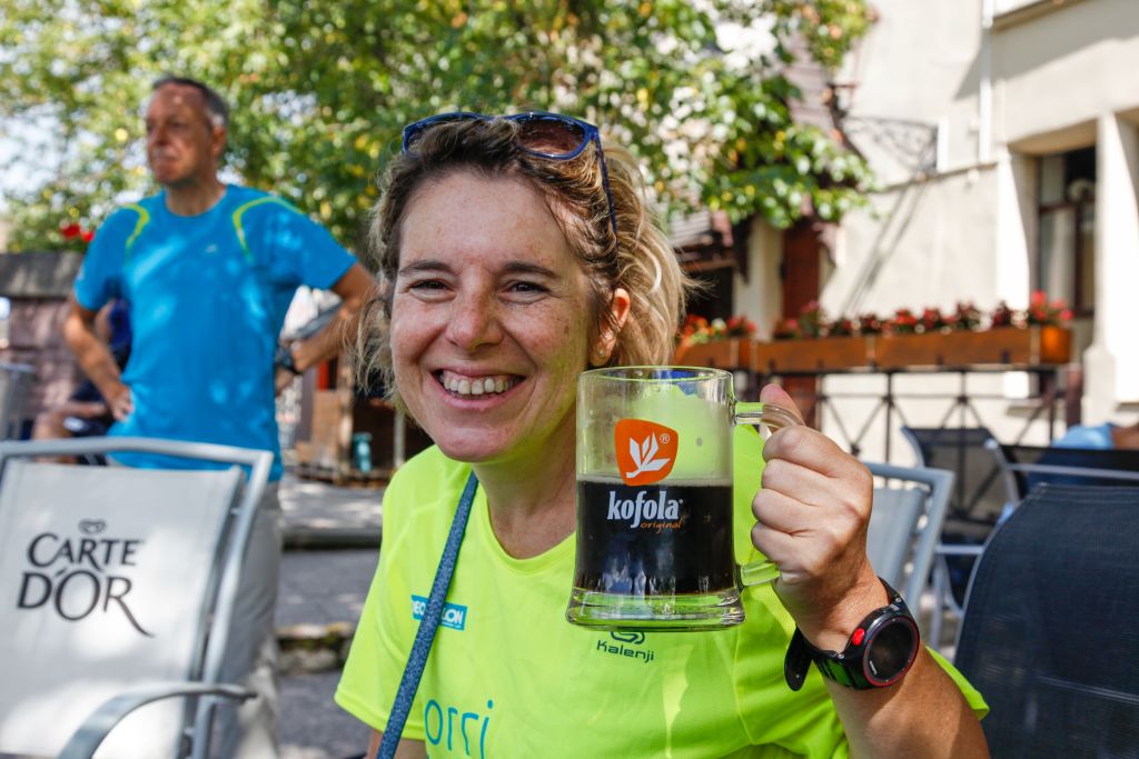 Ciclista che sorride e tiene in mano un boccale di birra, relax dopo una giornata in bici