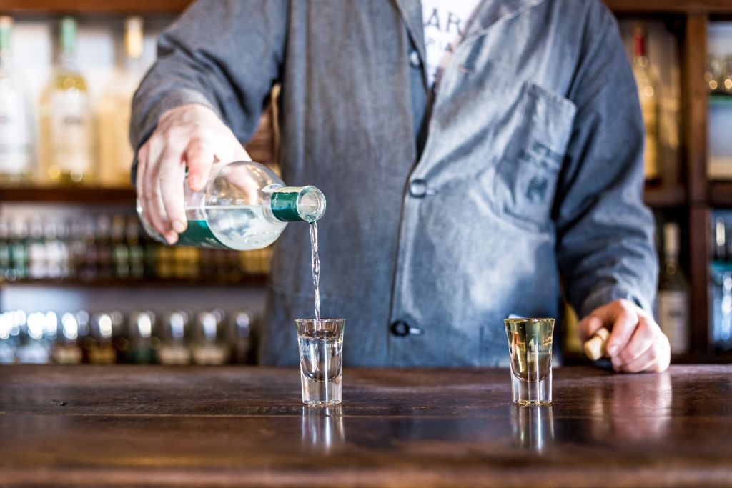 Due bicchierini di vetro in cui viene versata della grappa, enoteca, vacanza in bici, Veneto