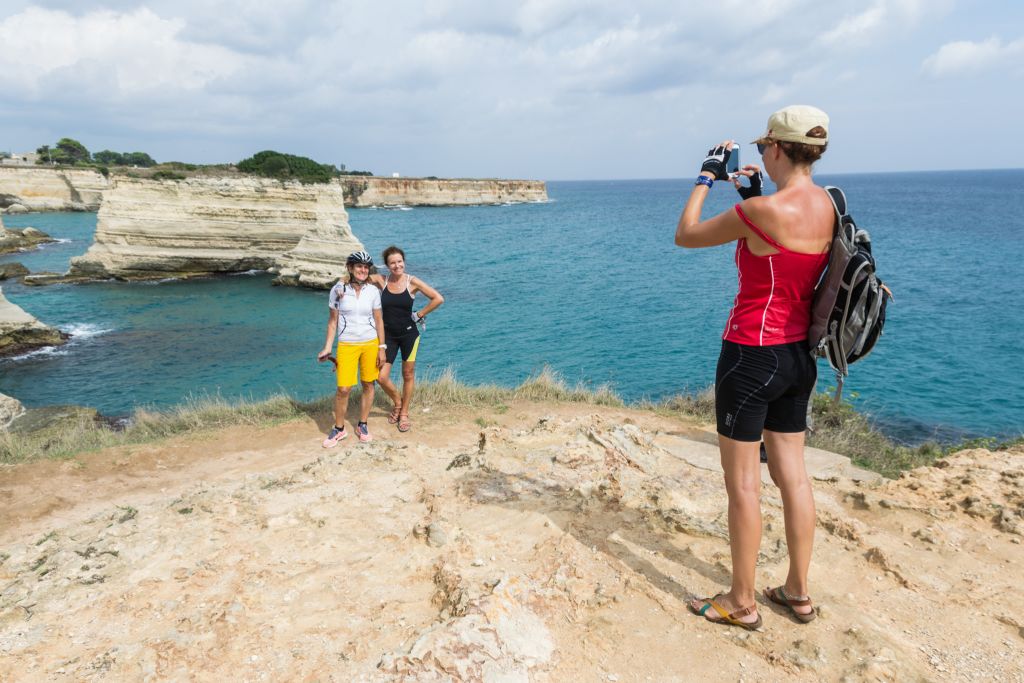 Urlauber machen Fotos an der felsigen Küste des Salento-Meeres