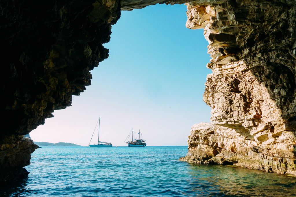Arco naturale di roccia con vista sull'acqua azzurra.