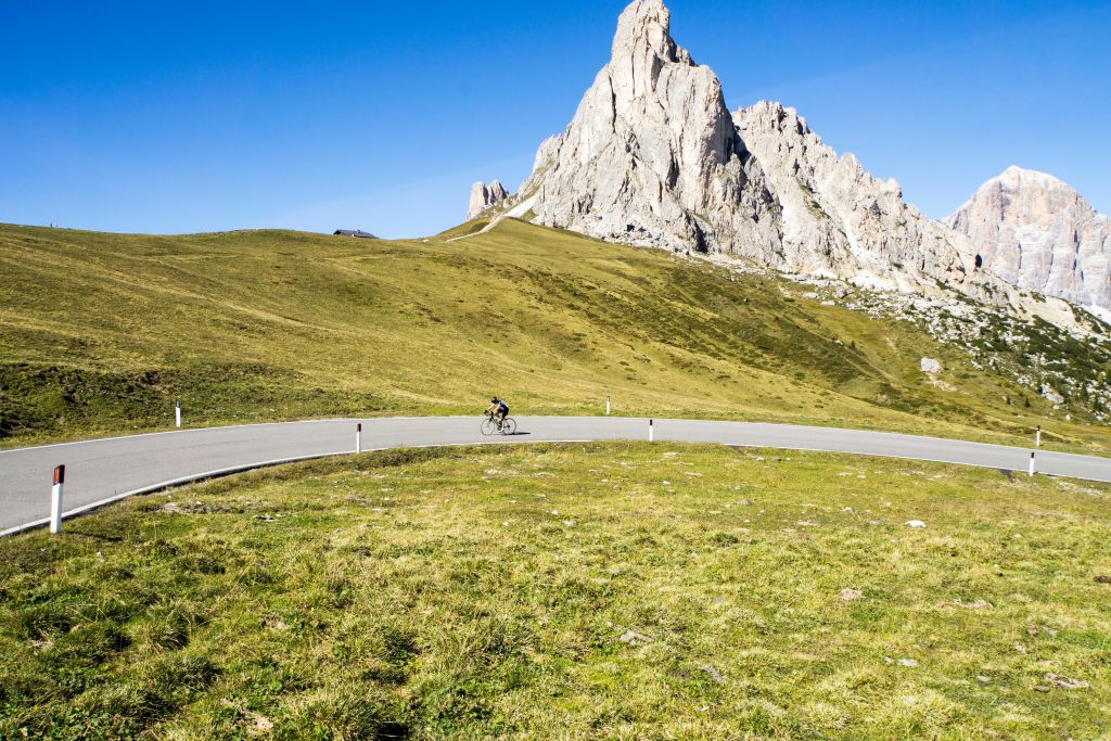 Ciclista solitario su una strada panoramica con le Dolomiti sullo sfondo, Italia in bici da corsa