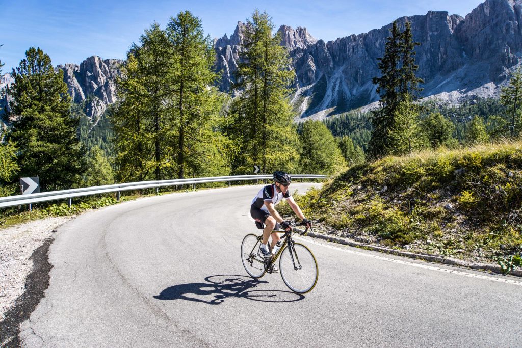Ciclista solitario in salita su una strada di montagna, tour in bici, Trentino Alto Adige in bici da corsa