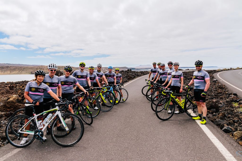Squadra di ciclisti in pausa con le biciclette sul ciglio della strada, tour cicloturistico, Lanzarote, turismo in bici, Spagna