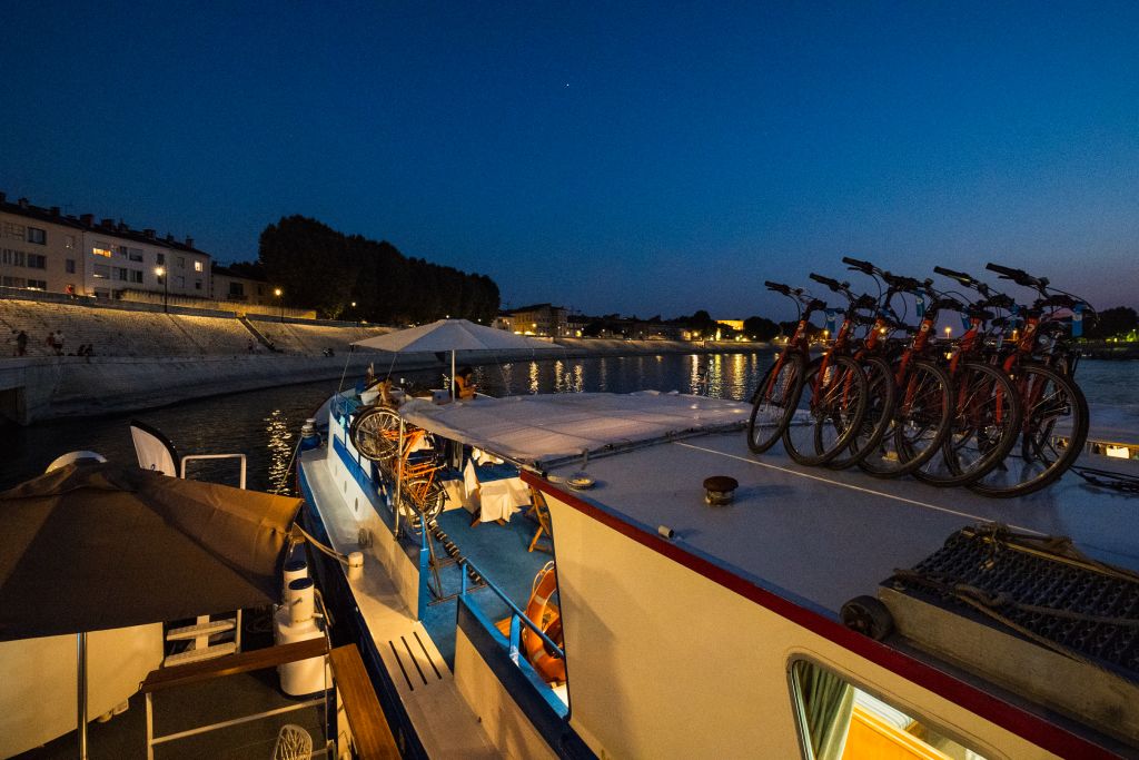 Bici parcheggiate sul ponte esterno barca di sera col buio, baia illuminata di sera, Francia