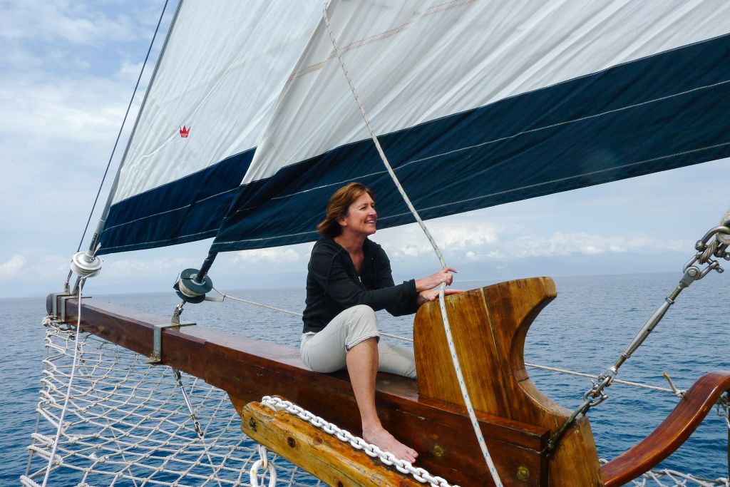 Donna che guida una barca a vela nel Mar Egeo, Grecia.