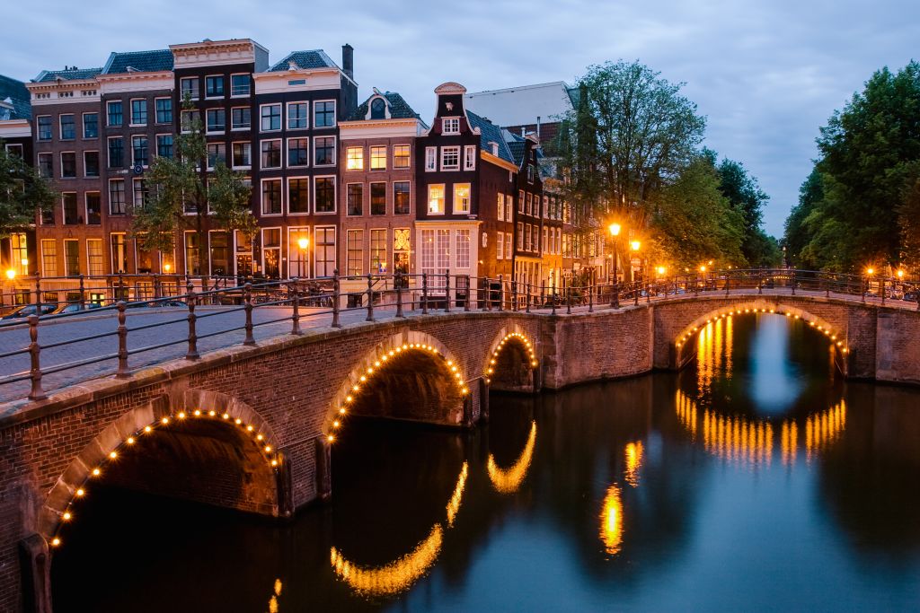 Beleuchtete Brücken am Abend über den Kanälen von Amsterdam, Holland.