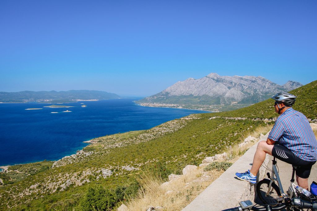 Ciclista ammira il panoramica delle colline e del mare Adriatico, Dalmazia