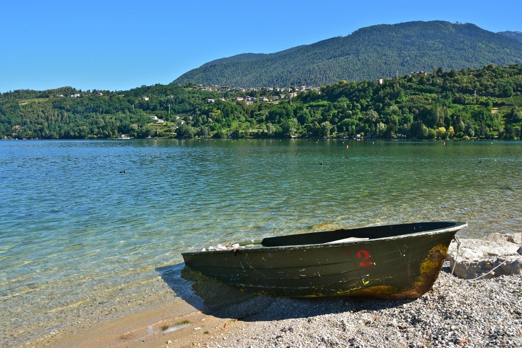 Piccola barca in legno in riva al lago tra le montagne