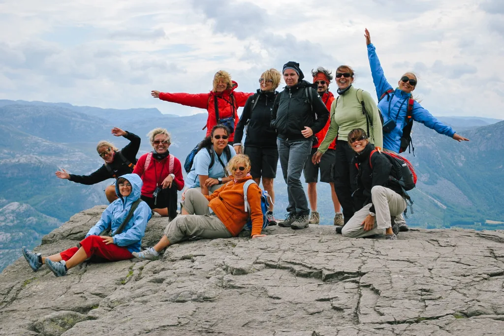 Tour di gruppo con "Girolibero", turisti sorridenti sulla piattaforma panoramica di Preikestolen, Norvegia.