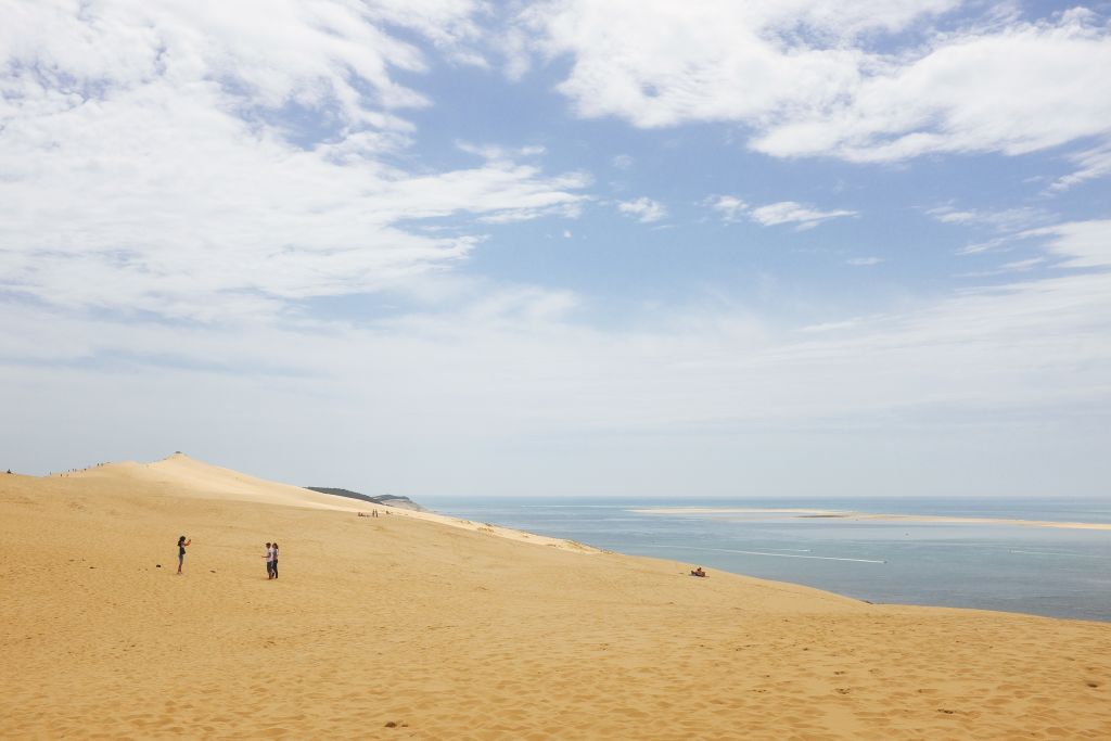 Vista della spiaggia e del mare calmo sotto un cielo parzialmente nuvoloso.