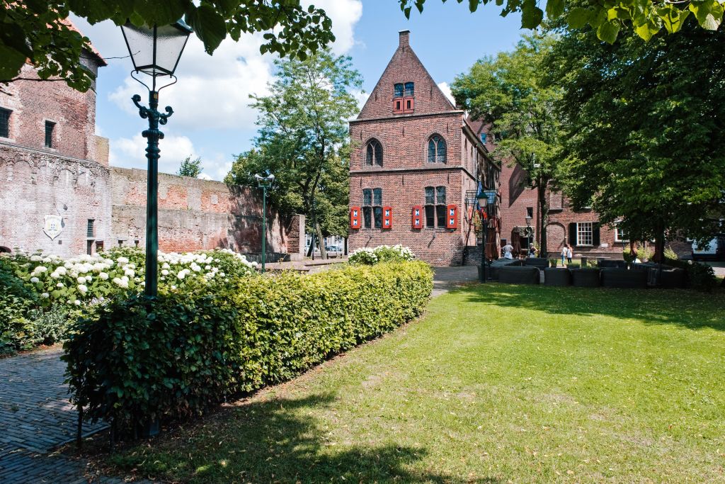 Edificio in mattoni tipico olandese in pietra con torri e mura, circondato da un prato.