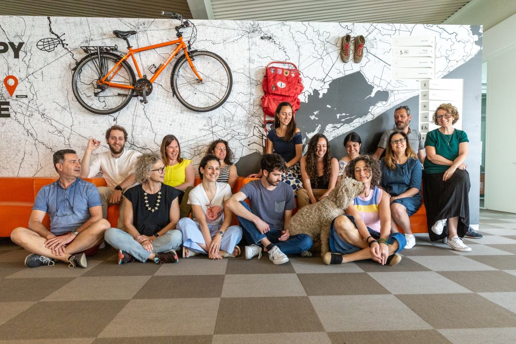 Girolibero team posing in front of hanging bicycles, Vicenza headquarters