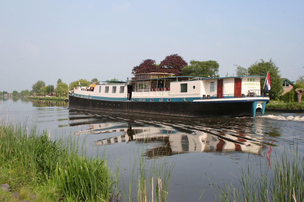 Chiatta galleggiante "La Mar" in navigazione in un canale con paesaggio rurale olandese