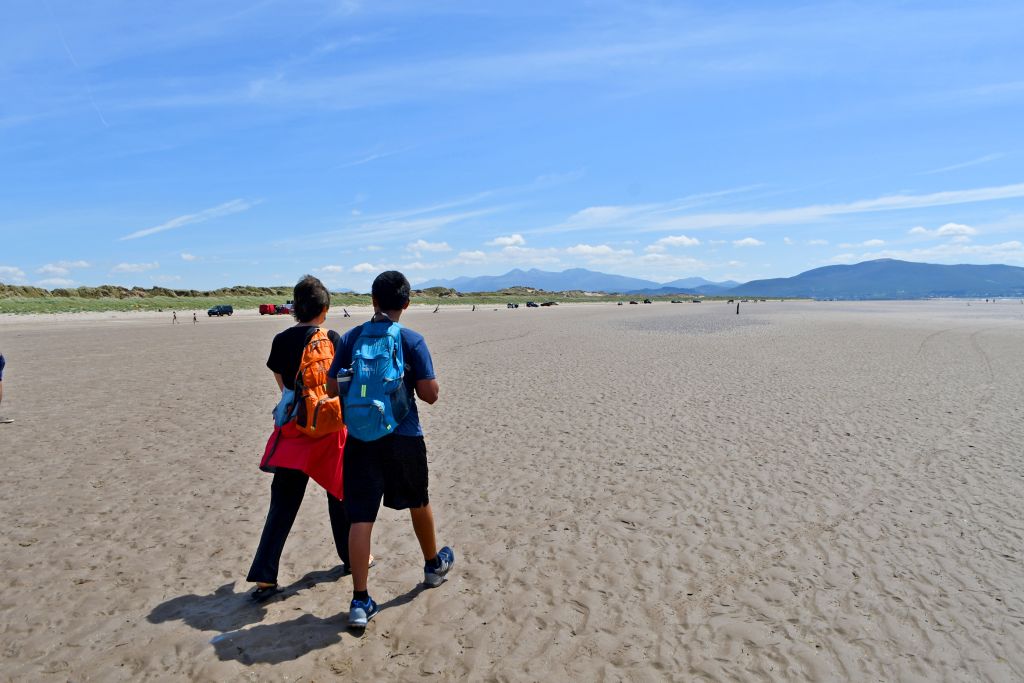 Coppia che cammina su una spiaggia sabbiosa con colline sullo sfondo, Irlanda da Cork al Kerry