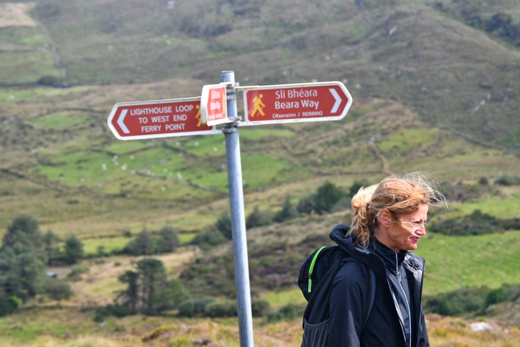 Escursionista vicino a un segnale turistico che indica la direzione lungo il percorso tra Cork e Kerry.