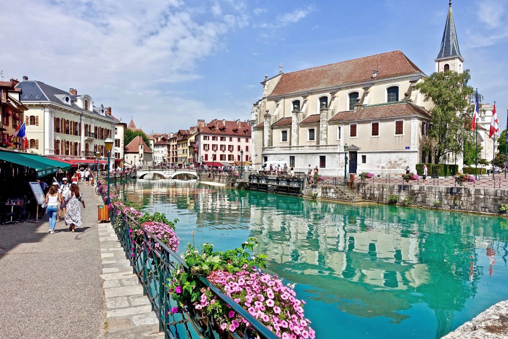 Case tradizionali lungo un canale fiorito nel centro storico di Ginevra.