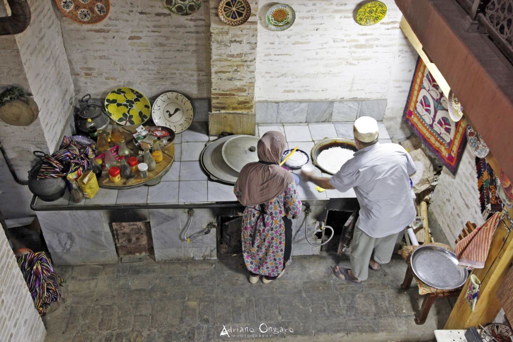 Panettieri uzbeki che cuociono il pane “non” in un forno tandoor tradizionale in Uzbekistan