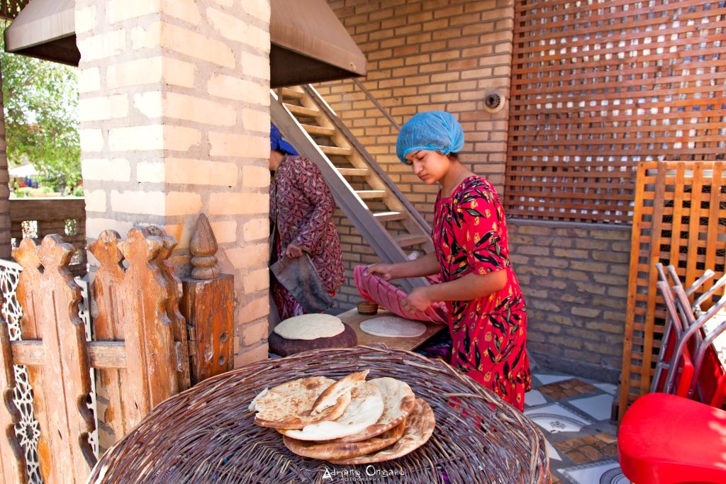 Donna uzbeka che cuoce il pane “non” in un forno tandoor tradizionale, Uzbekistan