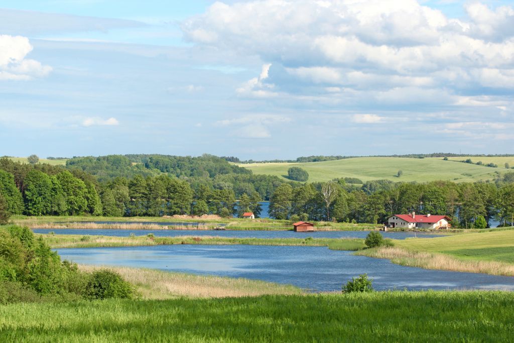 Panoramica di un lago con vegetazione costiera e colline sullo sfondo nei Laghi Masuri, Polonia.