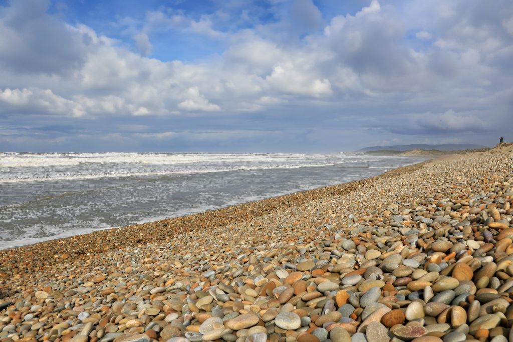 Spiaggia di ciottoli lungo la costa atlantica nel nord del Portogallo, con onde che si infrangono.