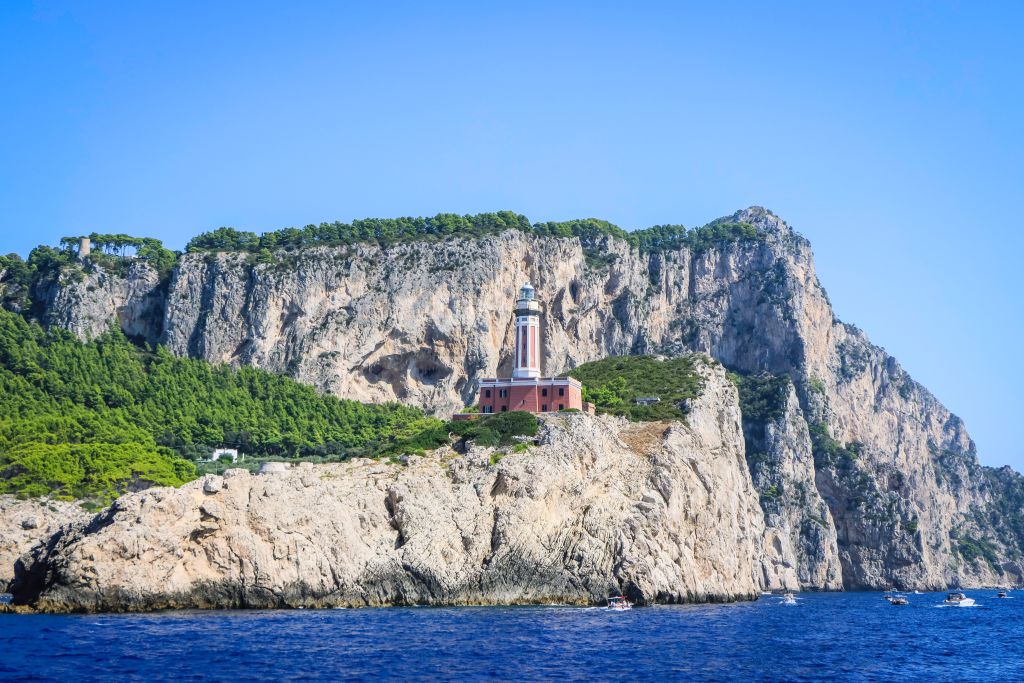 Scogliera di Punta Carena con il faro in lontananza, Capri, Italia.