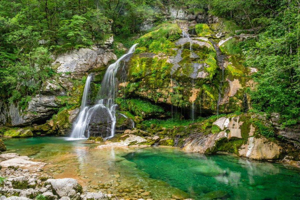 Cascata di Virje con piscina verde smeraldo e vegetazione rigogliosa, Alpi Giulie, Slovenia.