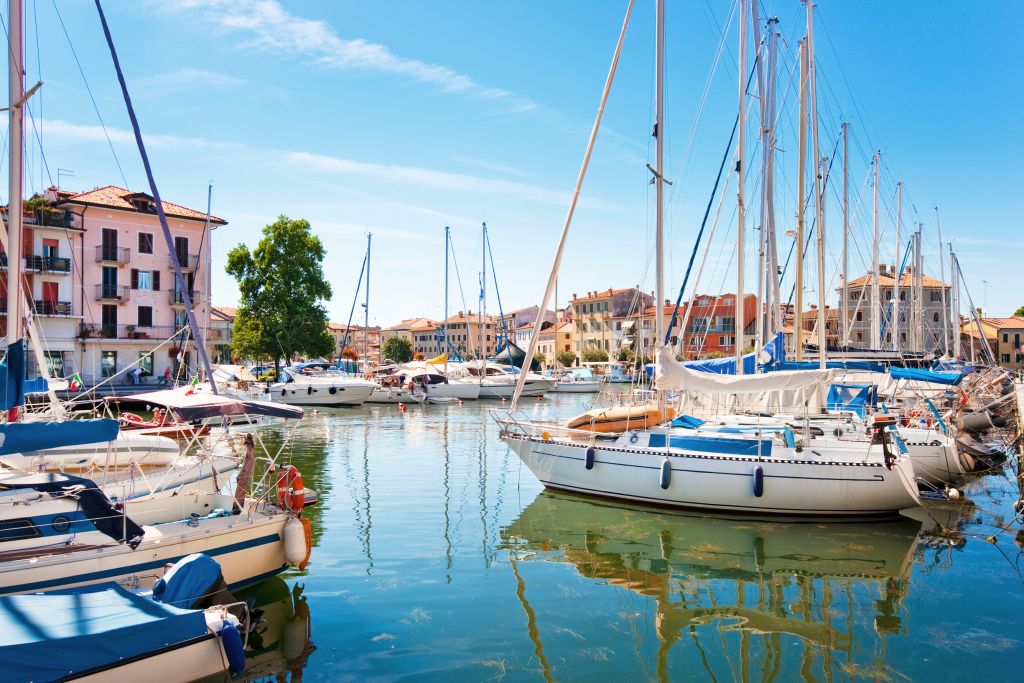 Porto di Grado, Italia, con barche ancorate e ciclisti in arrivo dalla Ciclovia Alpe Adria.