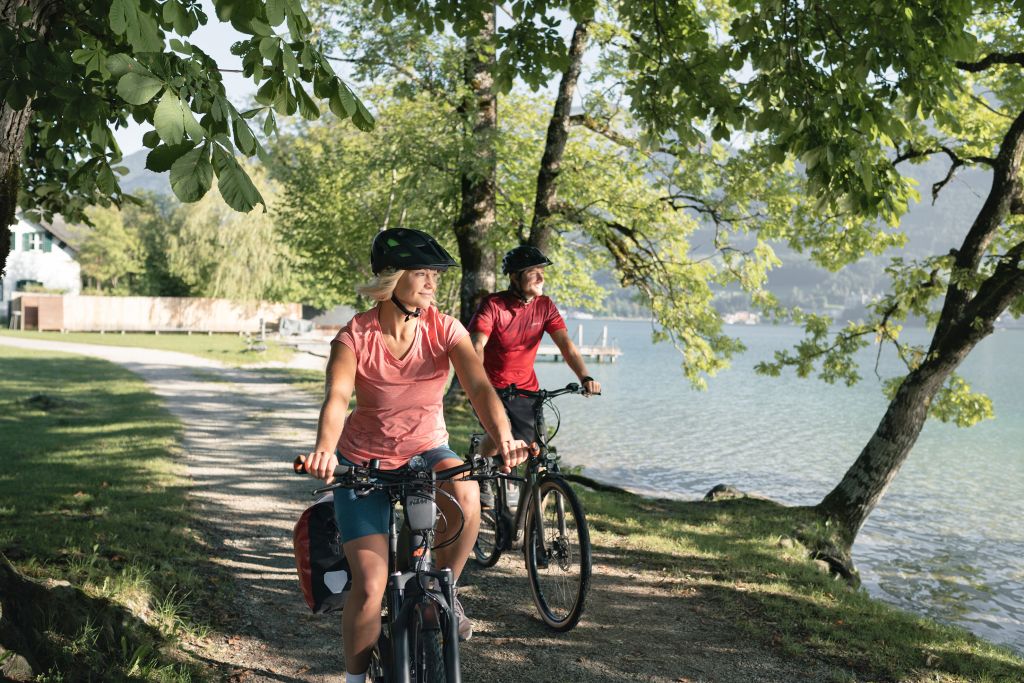 Coppia in bicicletta sotto alberi ombrosi lungo la pista ciclabile verso Vienna.