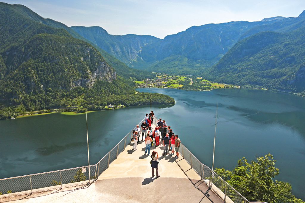 Turisti su una terrazza panoramica con vista sul lago Hallstättersee e le montagne circostanti.