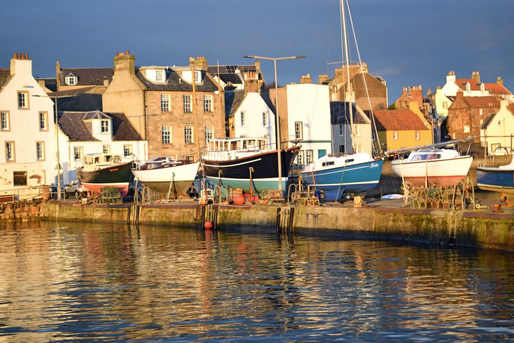 Porto di Pittenweem con barche e case tradizionali lungo la costa scozzese.