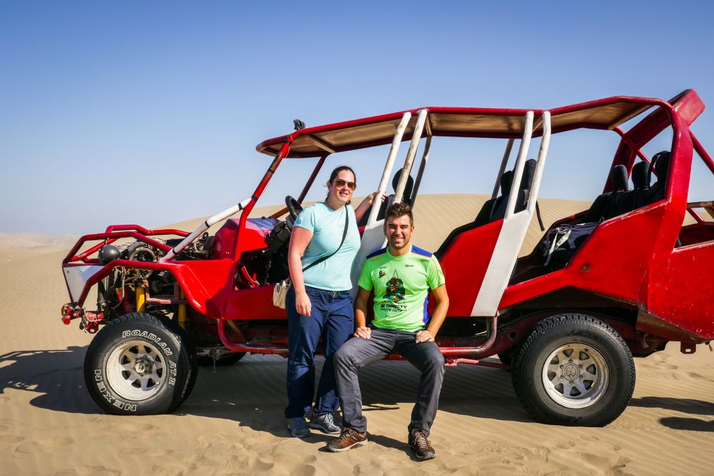 Turisti con un veicolo fuoristrada rosso su un sentiero desertico in Perù.
