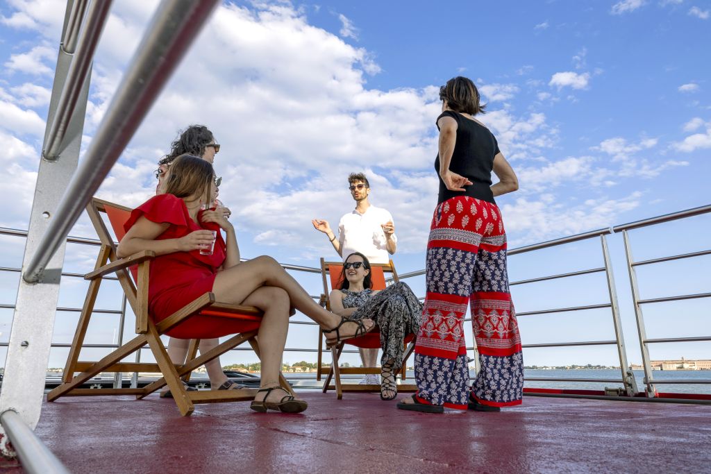 Gruppo di persone parlano sedute sulle sdraio sul ponte esterno di "Ave Maria"