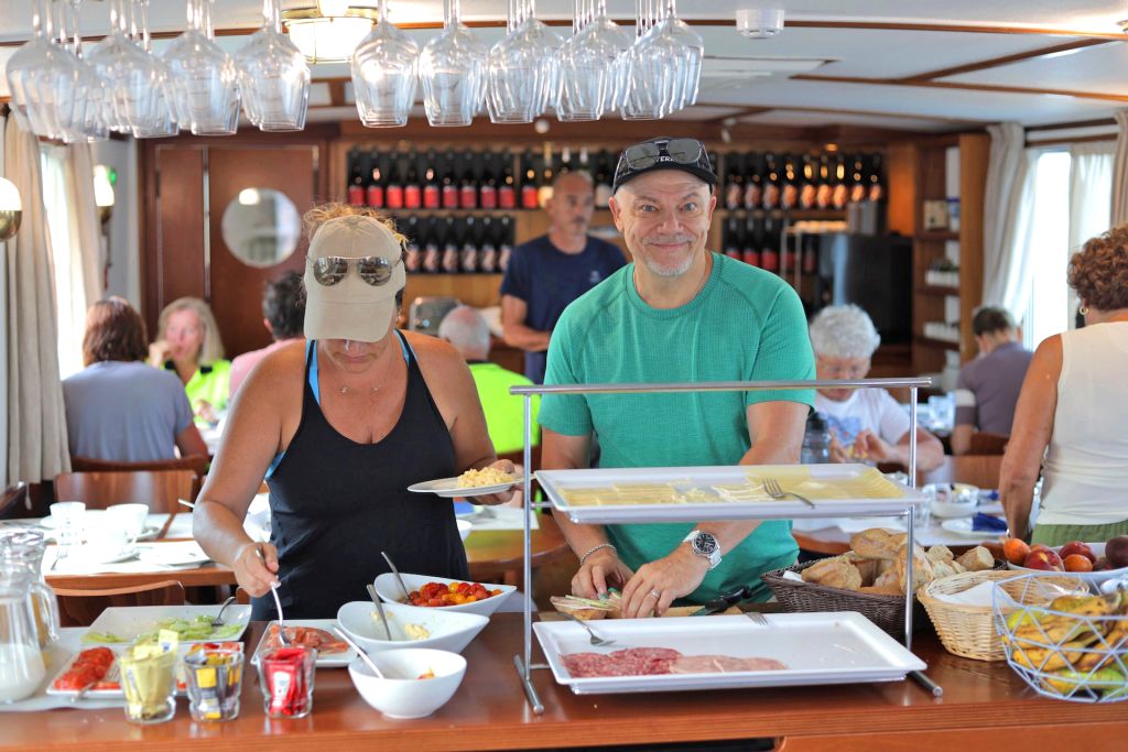 Due persone si servono durante un pranzo a buffet in barca "Caprice", viaggi bici e barca "Girolibero"