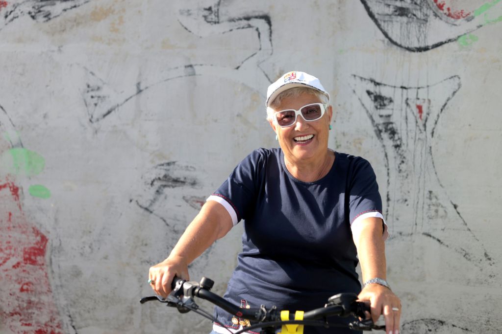 Cyclist in a dark shirt standing next to a stone wall, taking a break during a bike route in a historic or rural area.