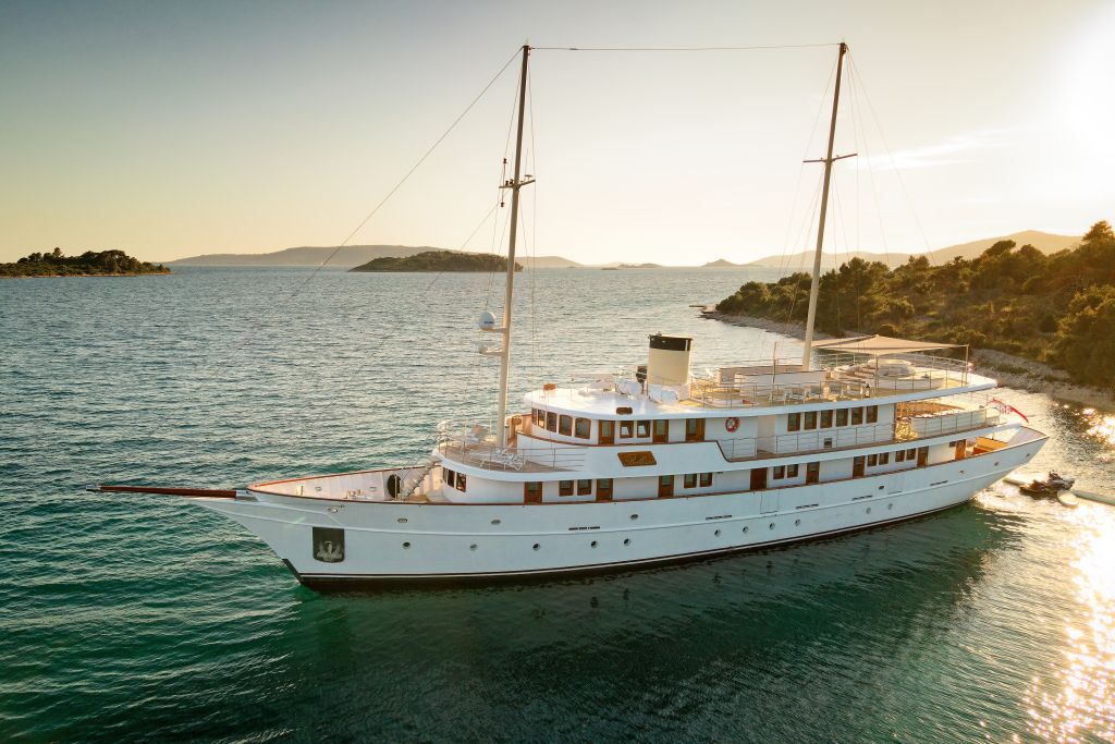 White ship sailing at sunset along the Dalmatian coast, Croatia.