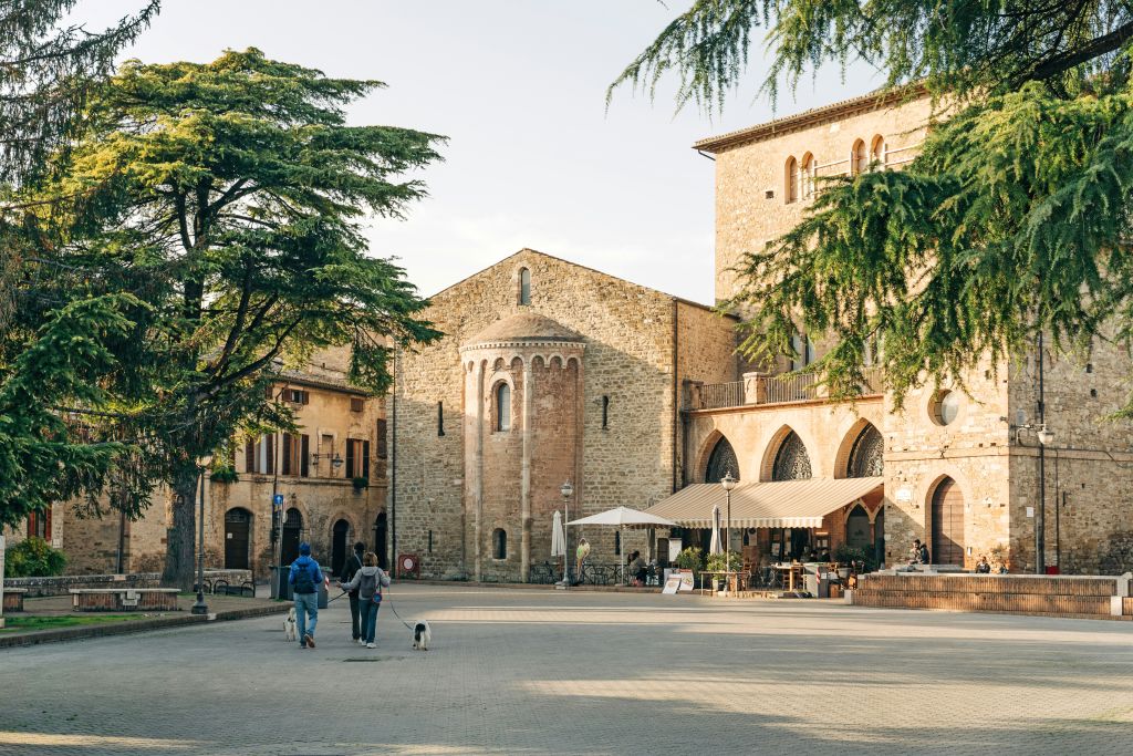 Centro storico di Bevagna con Piazza Silvestri, edifici medievali e persone che passeggiano.