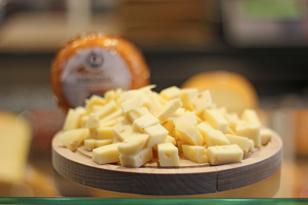 Assaggio di formaggi olandesi tipici, tagliati a cubetti e serviti in una ciotola di legno in un mercato locale.