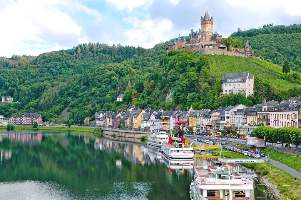 Panorama sul fiume Mosella e il Castello di Cochem, con case colorate lungo il fiume.