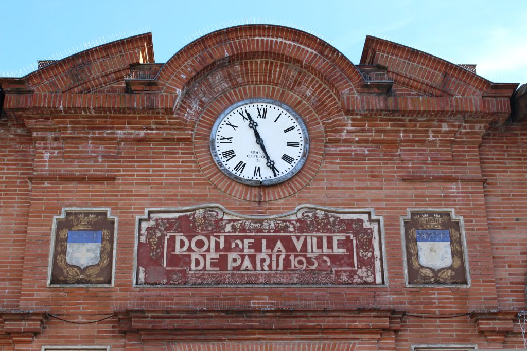 Facciata in mattoni rossi con orologio centrale a Moissac, Francia.