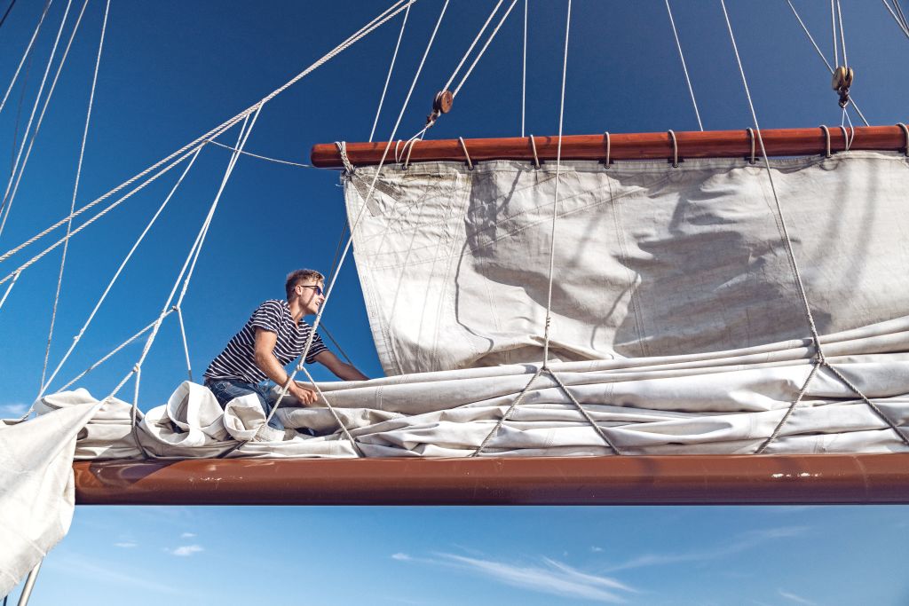 Sailor adjusting the sails on a traditional Dutch schooner.