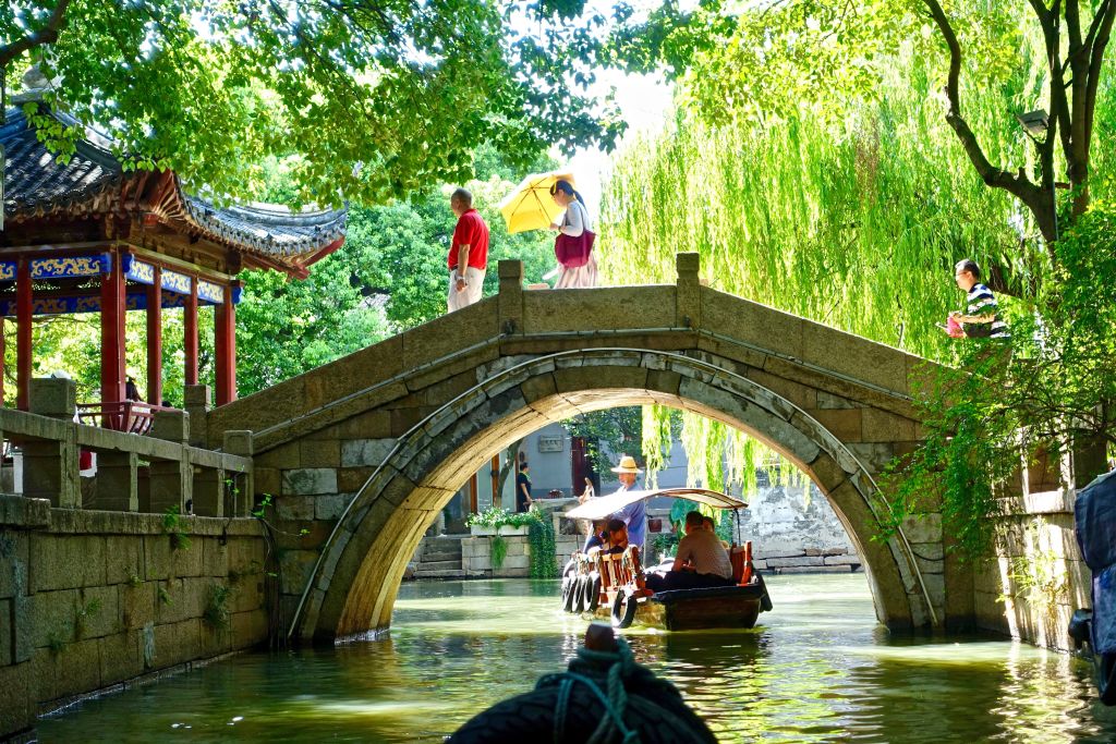 Barca tradizionale sotto ponte in pietra nel villaggio sull’acqua di Suzhou, esperienza autentica vicino a Shanghai